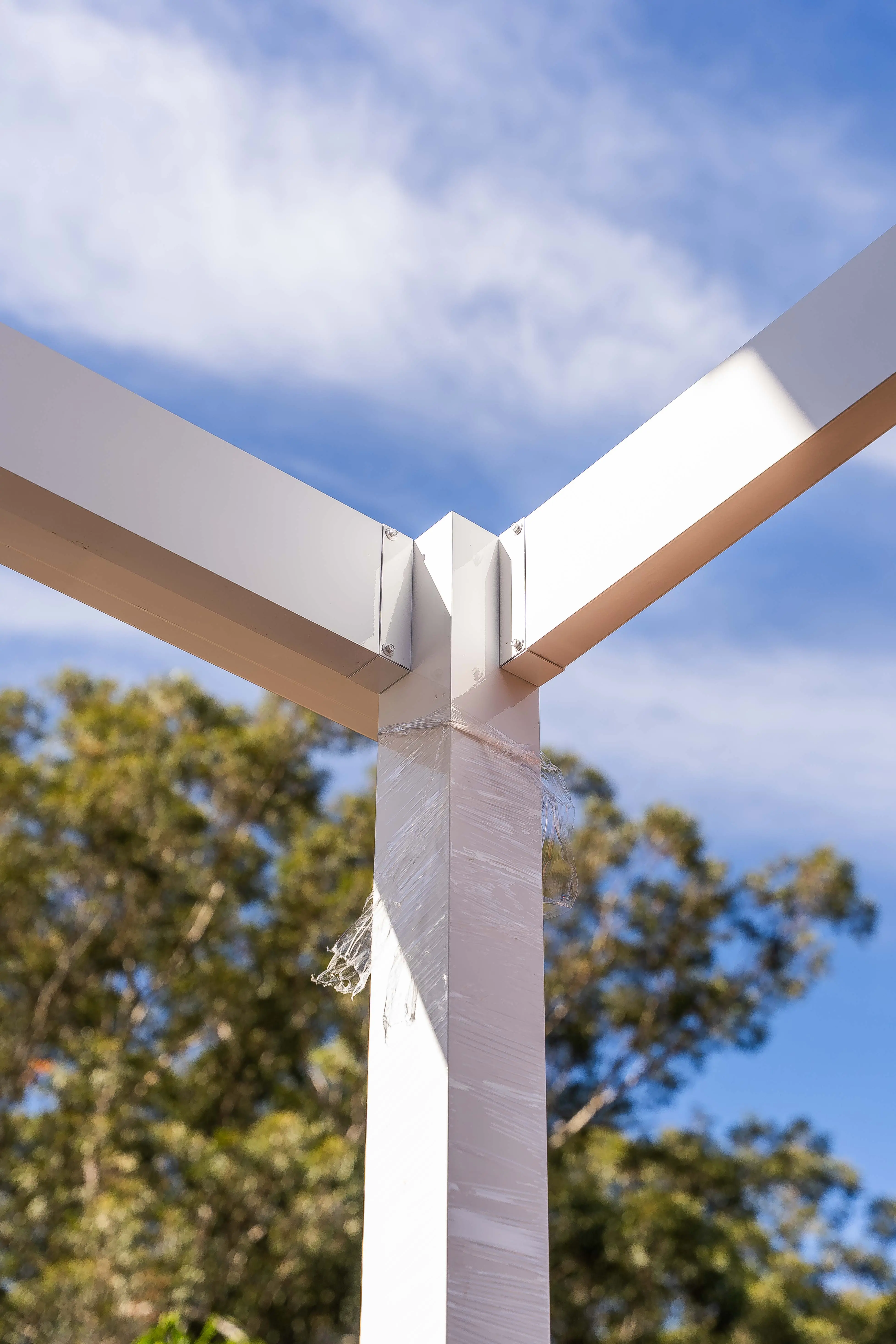 Portrait of gutter outlet and downpipe routing beside a support post